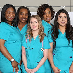 several nurses wearing teal scrubs in front of a privacy curtain