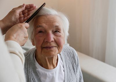 A caregiver combing the hair of an elderly woman