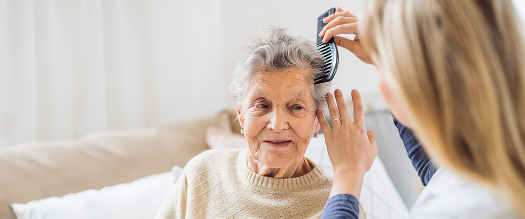 A caregiver combing the hair of an elderly woman