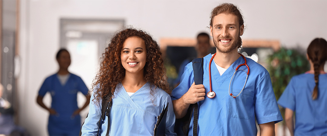 two young nurses in the hallway wearing blue scrubs